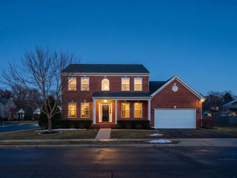 Two-story brick colonial at dusk with no holiday lighting