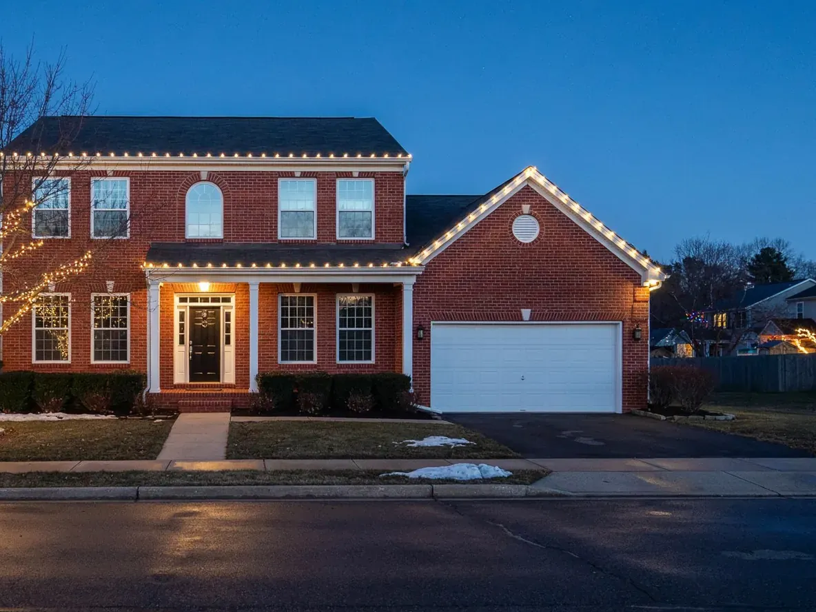 Mockup of the same colonial with warm white C9 lights along the roofline, porch, and garage gable